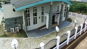 A modern house with a curved roof, satellite dishes, and a gated entrance. - Room-world Lilies Hotel-guest Room (Ibadan)