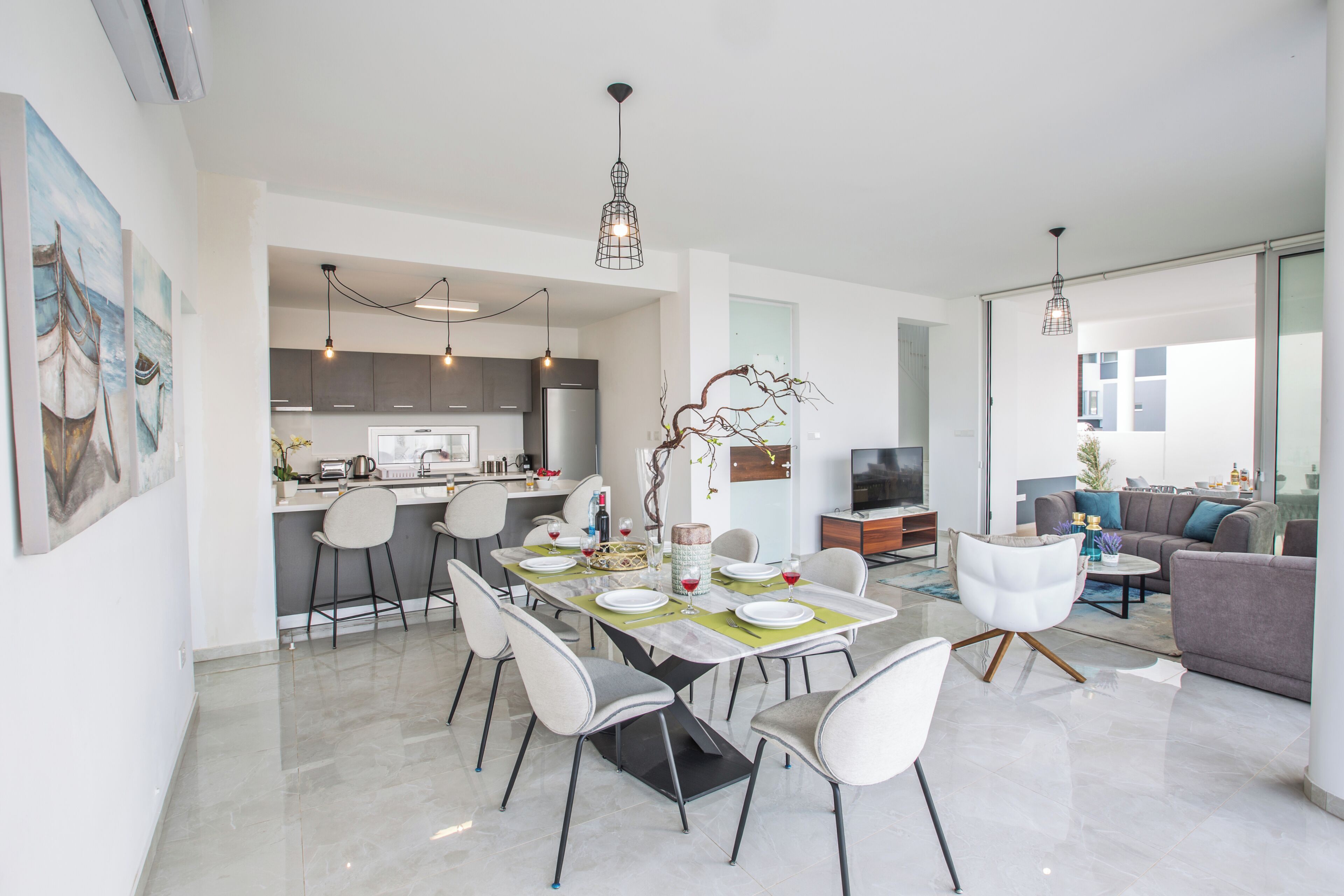 Um espaço de estar moderno e integrado, com área de jantar, cozinha e espaço para sentar.