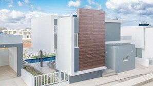 A modern residential building with a pool, white and grey exterior walls, and a wooden panel accent. - Villa Prol26, Stunning 3bdr Protaras Villa With Pool, Close to Fig Tree Bay (Paralimni)