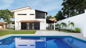 Une maison moderne à deux étages, avec une piscine en premier plan.