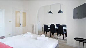 Una habitación de hotel con cama, una mesa de comedor con sillas y un televisor montado en la pared.