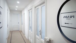 Un pasillo con puertas blancas, un radiador y un letrero en la pared.