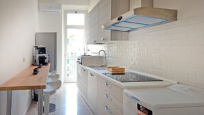 Una cocina moderna con una mesa de madera, horno integrado y salpicadero de azulejos blancos.