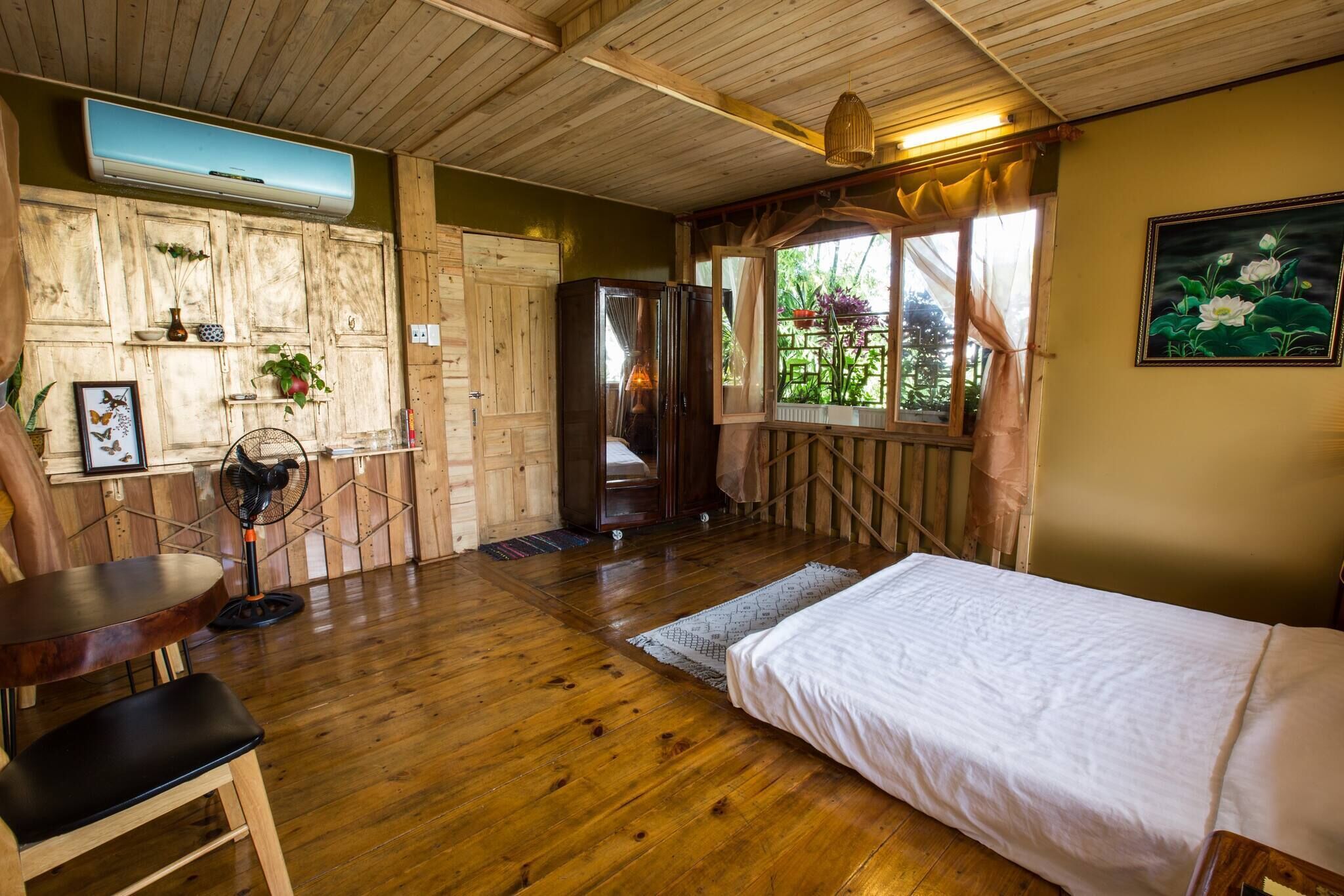 A wooden-floored room with a bed, a table, and a chair.