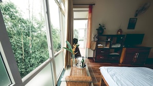 A bedroom with a bed, a small table with a plant, a TV, and a wardrobe. - Hillside Homestay Hue - Top Apartment (Hue)