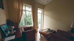 A living room with wicker furniture, a glass coffee table, and a TV on a wooden stand. - Hillside Homestay Hue - Top Apartment (Hue)