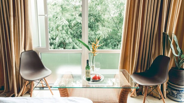 A room with a glass table, two chairs, a bottle, and a glass of water. - Hillside Homestay Hue - Top Apartment (Hue)