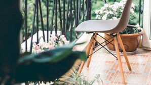 A balcony with a chair and potted plants, a tiled floor, and a metal railing. - Hillside Homestay Hue - Top Apartment (Hue)