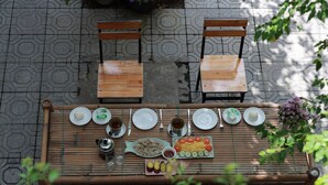 A bamboo table set with plates, bowls, and utensils, surrounded by wooden chairs.