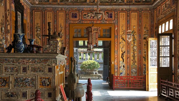 An ornate interior with traditional Chinese architectural elements, including intricate wall carvings and a central courtyard with a tree. - Hillside Homestay Hue - Silk Room (Hue)