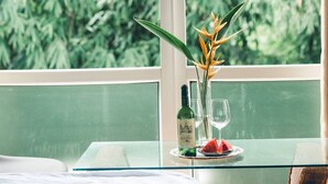 A table with a bottle, two glasses, and a fruit slice by a window with a view of greenery. - Hillside Homestay Hue - Triple Room top Apartment (Hue)