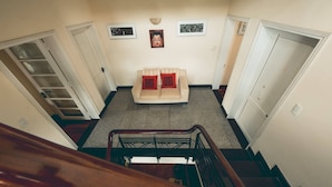 A hallway with a beige sofa, two red pillows, and a framed picture on the wall. - Hillside Homestay Hue - Triple Room top Apartment (Hue)