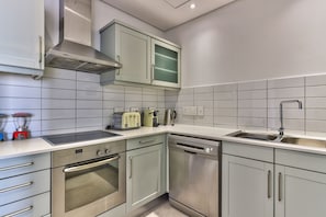 Enjoy cooking in this well-lit kitchen with a range hood, sink, and modern appliances.