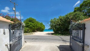 Une allée bordée de portails menant à une plage, avec un ciel bleu dégagé.