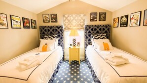 A hotel room with two beds, star-patterned floor, navy-themed wall art, and a central window with patterned curtains. - Go Navy! Steps to USNA, City Dock & Street Parking (Annapolis)