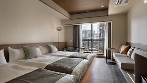 Habitación de hotel con una cama grande, un sofá, una mesita y vistas a la ciudad desde un balcón.