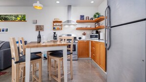 Una cocina compacta con armarios de madera, un refrigerador de acero inoxidable y una zona de comedor con mesa y sillas de madera.
