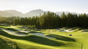 A golf course with sand bunkers and a clear view of mountains in the background.