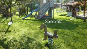 Un parque infantil con un tobogán, un columpio y un conjunto de columpios con un muelle azul.