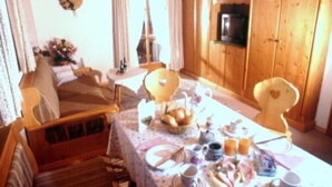 Un comedor acogedor con una mesa preparada para el desayuno, muebles de madera y vistas a la Torre Eiffel a través de un ventanal.
