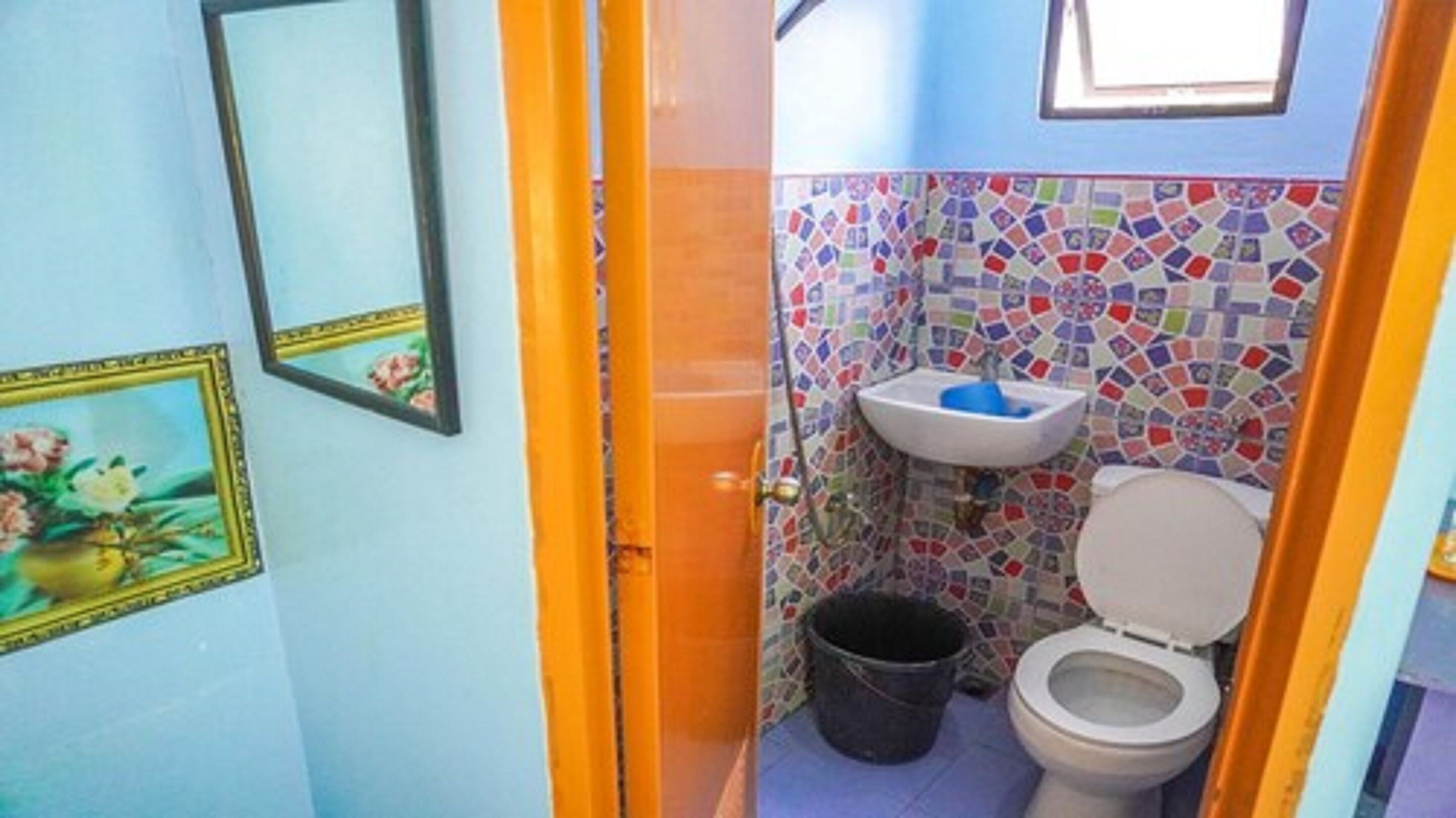 A small bathroom with a toilet, sink, and a bucket.