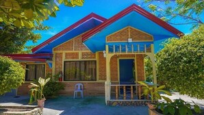 Une maison à deux étages avec un toit rouge, de grandes fenêtres et un petit porche.