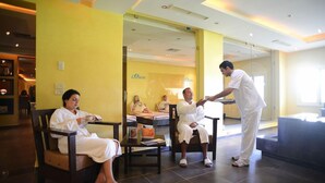 Un hall d'hôtel avec un comptoir d'accueil, un espace salon et un lit visible au fond.