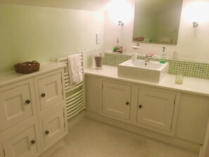 A bathroom with white cabinets, a sink, a mirror, and a towel rack.