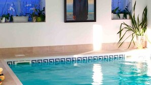 An indoor swimming pool with a framed painting on the wall. - Luxury Accom With Pool Henbury Macclesfield (Macclesfield)