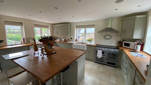 A spacious kitchen with a central island, a stove, oven, microwave, and ample counter space. - Luxury Accom With Pool Henbury Macclesfield (Macclesfield)