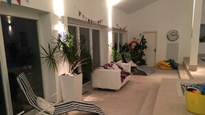 A spacious indoor area with a pool, lounge chairs, and potted plants. - Luxury Accom With Pool Henbury Macclesfield (Macclesfield)