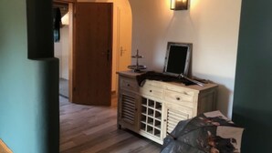 A room with a wooden door, a dresser with drawers, a mirror, and a wall-mounted light fixture. - Ferienwohnung Hochgern (Grassau)