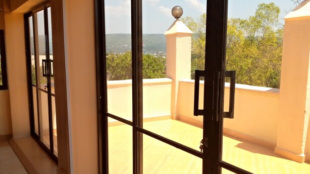 Un couloir doté de grandes portes vitrées qui donnent sur une terrasse sur le toit, offrant une vue sur la verdure et les collines lointaines.