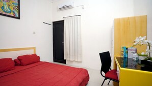 A room with a bed, a desk, a chair, a door, and an air conditioner. - Dparagon Pamela 4 (Depok)