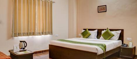 A hotel room with a bed, bedside tables, a coffee maker, and a window with curtains.