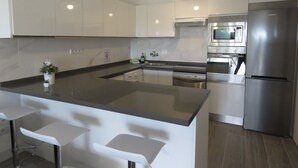 Een moderne keuken met een centraal eiland, roestvrijstalen apparatuur en witte kasten.