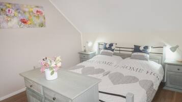 A bedroom with a bed, nightstands, a dresser, and a painting on the wall.