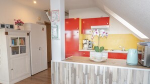 Une cuisine moderne avec un îlot central en bois, des armoires rouges et un pare-feu jaune.
