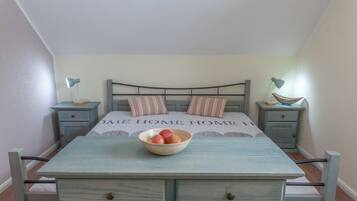 A bedroom with a bed, two bedside tables, a nightstand, a dresser, and a bowl of fruit on the dresser.