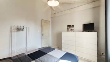 Een slaapkamer met een bed, een kledingkast, een televisie en een stadsbeeld aan de muur.