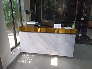 A reception desk with a marble counter, a laptop, a sign requesting a mask, and a bottle of hand sanitizer. - Mersey Central Hanoi Apart'Hotel (Hanoi)