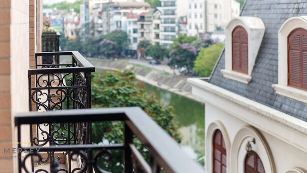 A balcony with wrought iron railings overlooking a canal and buildings. - Mersey Central Hanoi Apart'Hotel (Hanoi)