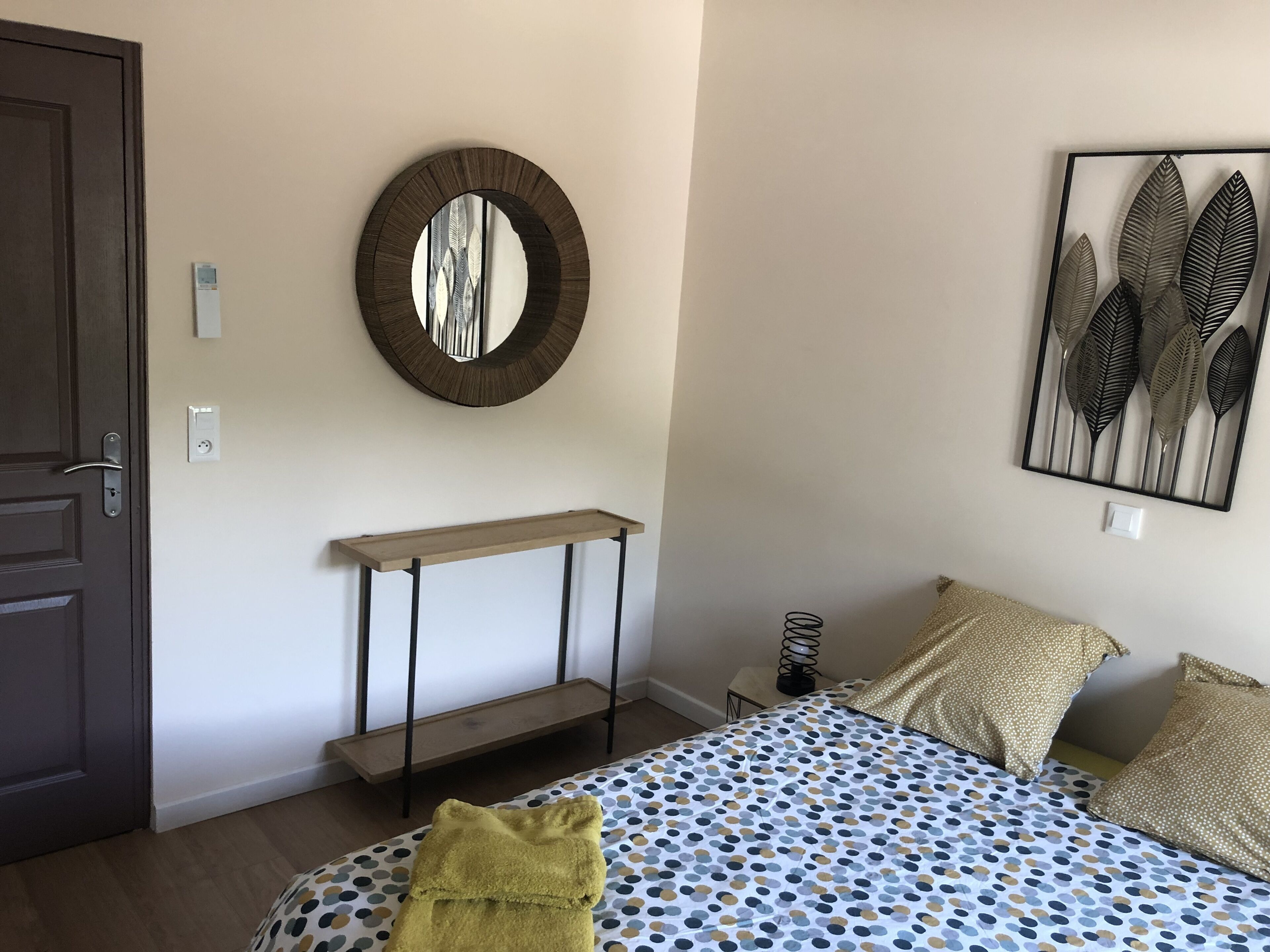 Um quarto com uma cama, uma mesinha de cabeceira, um espelho e uma obra de arte na parede.