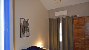 A bedroom with a bed, a wall-mounted air conditioner, and a wooden wardrobe. - La Magnanerie de L'estrade (rosières)