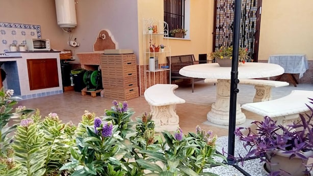 Un espace patio aménagé avec une table à manger, des tabourets blancs et des plantes en pot.