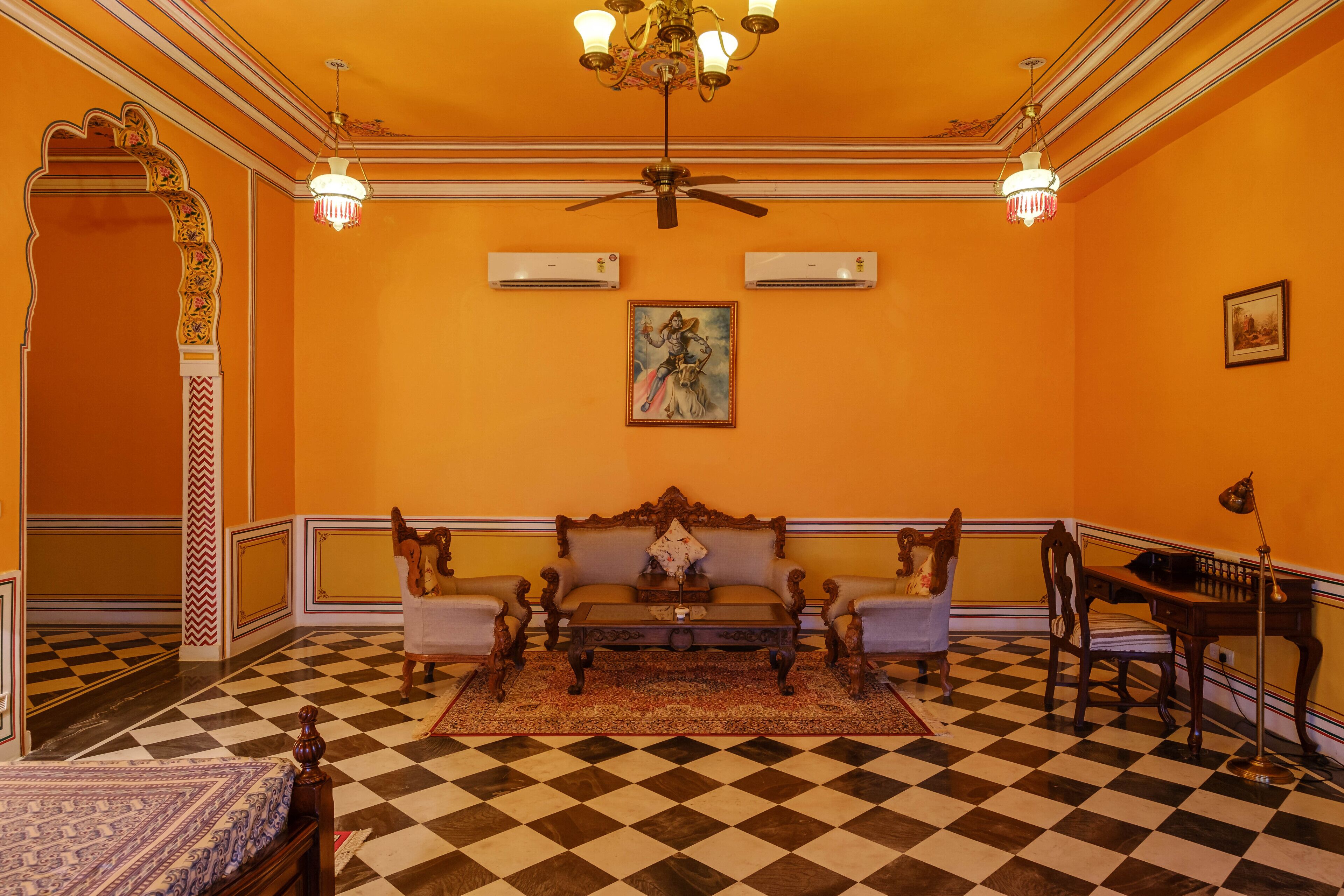 A room with a checkered floor, a sofa, a table, and a chandelier.