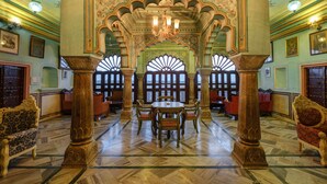 A grand hall with ornate arches, a central table, and seating arrangements. - Hotel Rajmahal Palace (Devli)