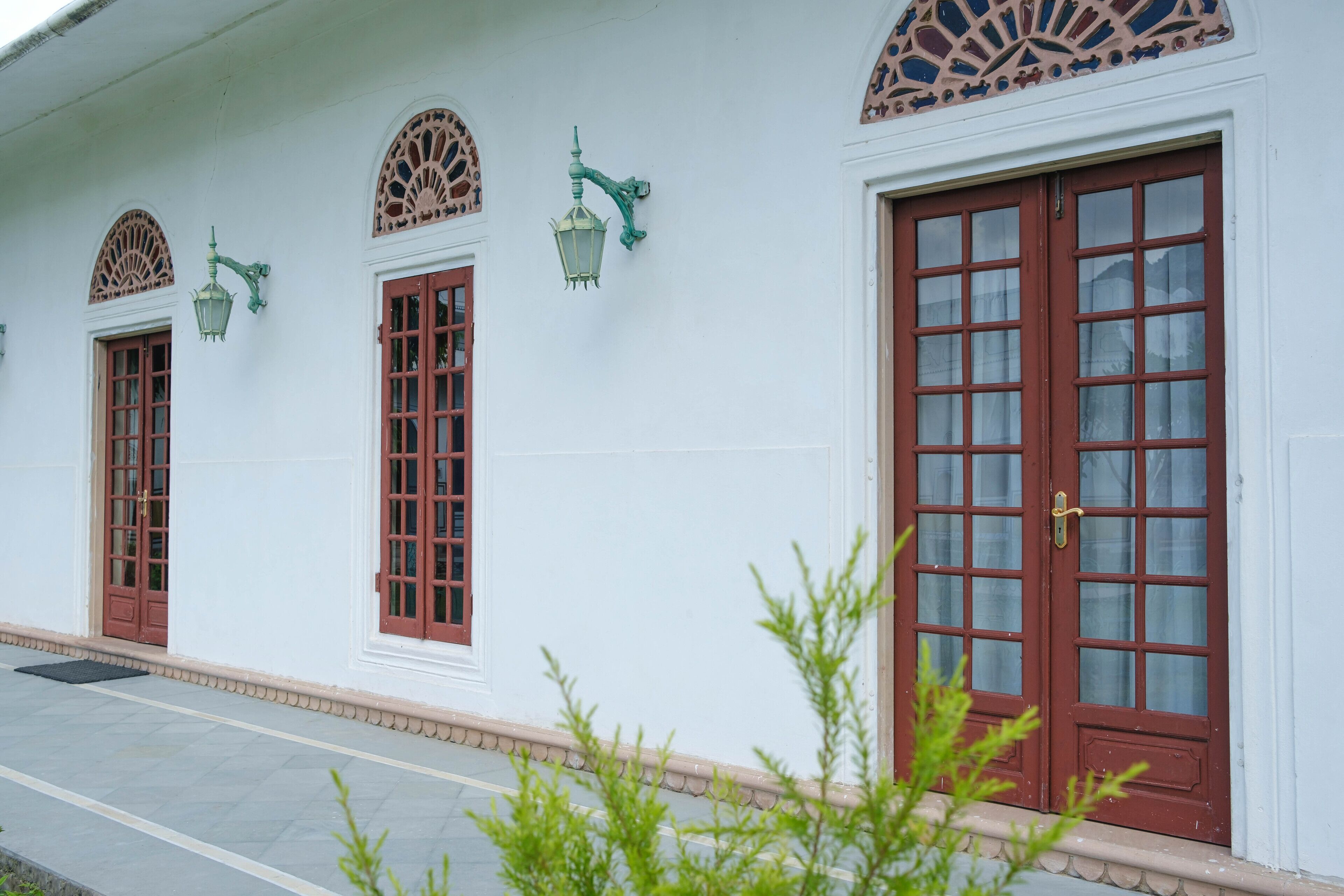 A building with three arched windows and a large door with a grid pattern.