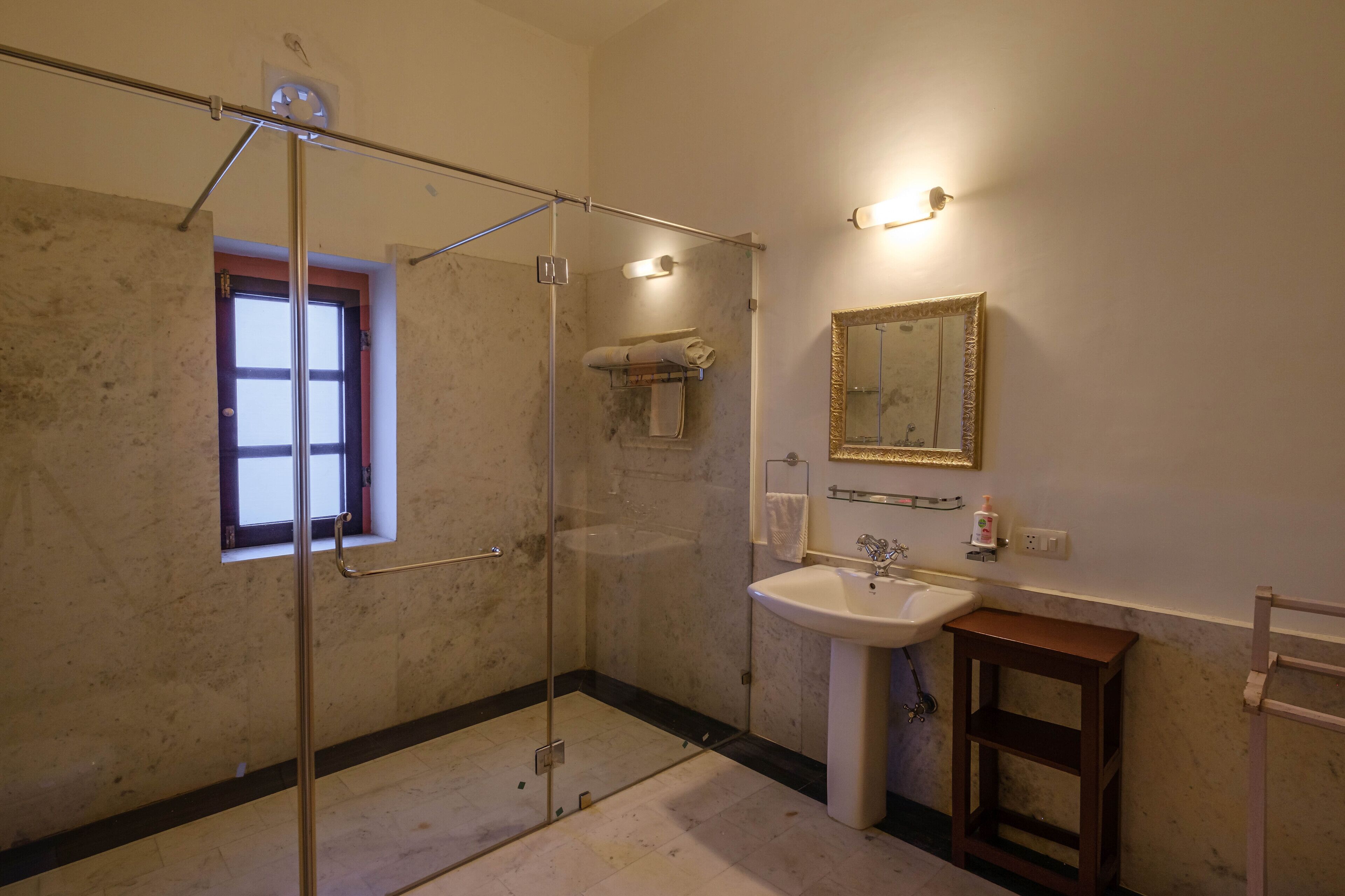 A bathroom with a glass shower enclosure, a sink, a mirror, and a towel rack.