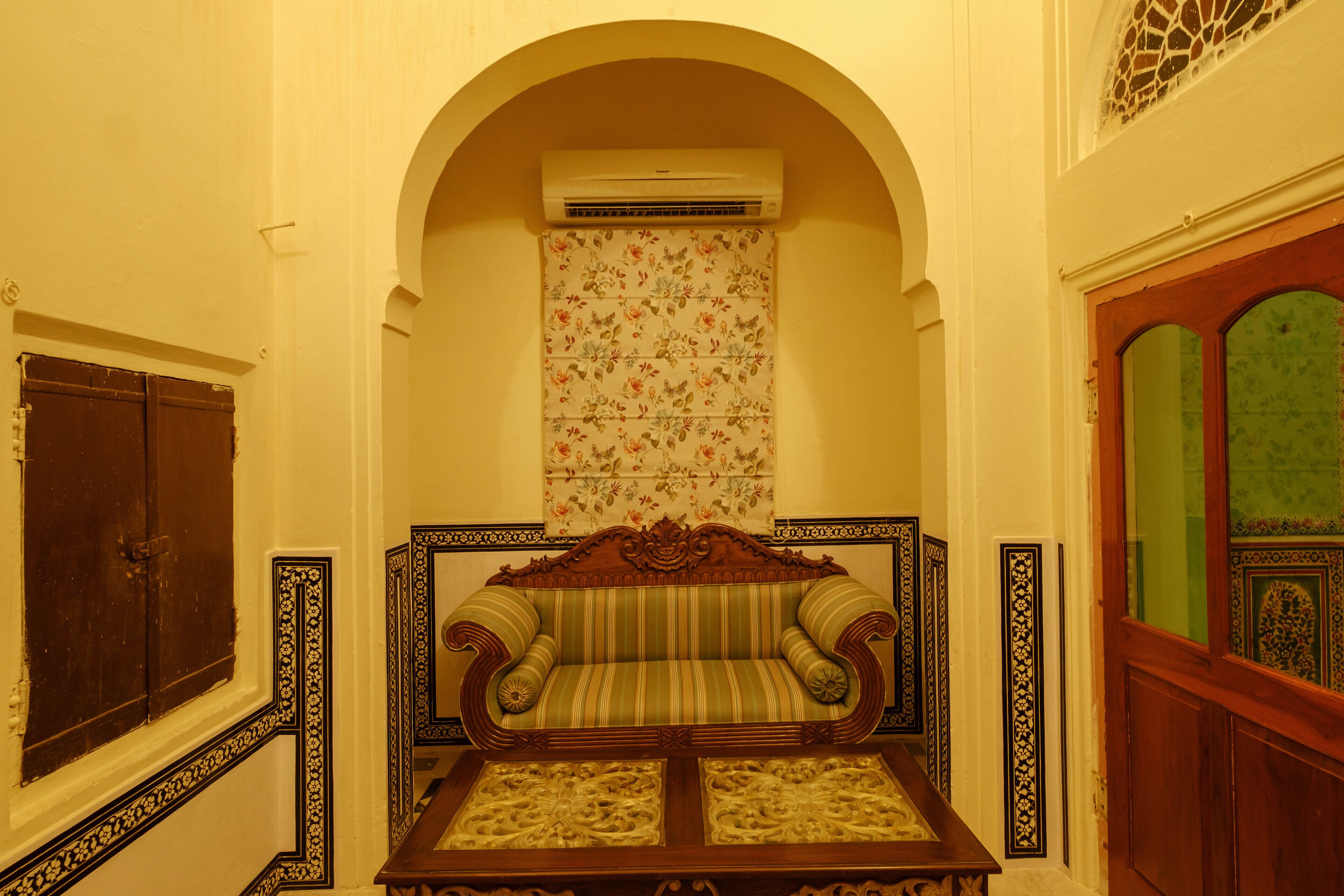 A room with a sofa, a decorative table, an arched doorway, and a patterned wall.